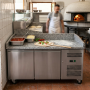 Table réfrigérée utilisée comme poste de préparation dans une cuisine professionnelle