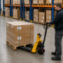 Transpalette peseur utilisé pour déplacer une palette de cartons dans un entrepôt.