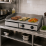 Plancha utilisée dans une cuisine professionnelle pour cuire différents aliments.