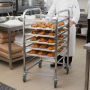 Chariot inox à glissières chargé de viennoiseries, utilisé en boulangerie professionnelle.