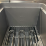 Vue intérieure d’une cuve de friteuse professionnelle avec résistance chauffante et grille de protection en inox.