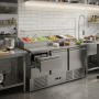 Mise en situation de la table réfrigérée dans une cuisine professionnelle moderne. Le meuble en inox est installé sous un espace