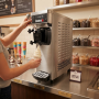 Machine professionnelle à sundae en inox installée sur le comptoir d’un établissement de restauration. Une personne actionne le 