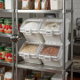 Quatre bacs à ingrédients blancs empilés sur une étagère en inox dans une cuisine professionnelle, contenant notamment du sucre,