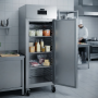 Armoire réfrigérée professionnelle en inox installée dans une cuisine professionnelle, porte ouverte et contenant différents ali