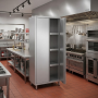 Armoire haute en inox à deux portes, installée dans une cuisine professionnelle équipée de plans de travail, d'étagères et d'app