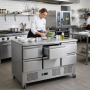 Table réfrigérée professionnelle à 6 tiroirs en acier inoxydable, installée dans une cuisine de restaurant. Une cheffe prépare d